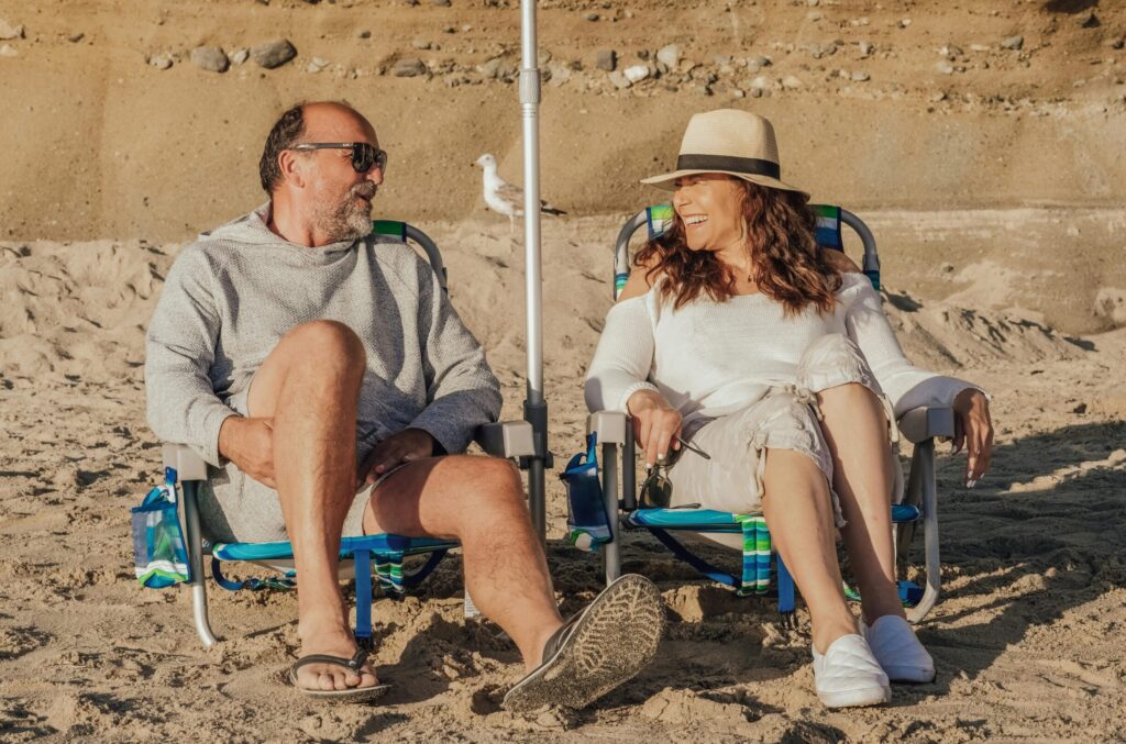 Happy senior couple seated on the beach enjoying a sunny day together.